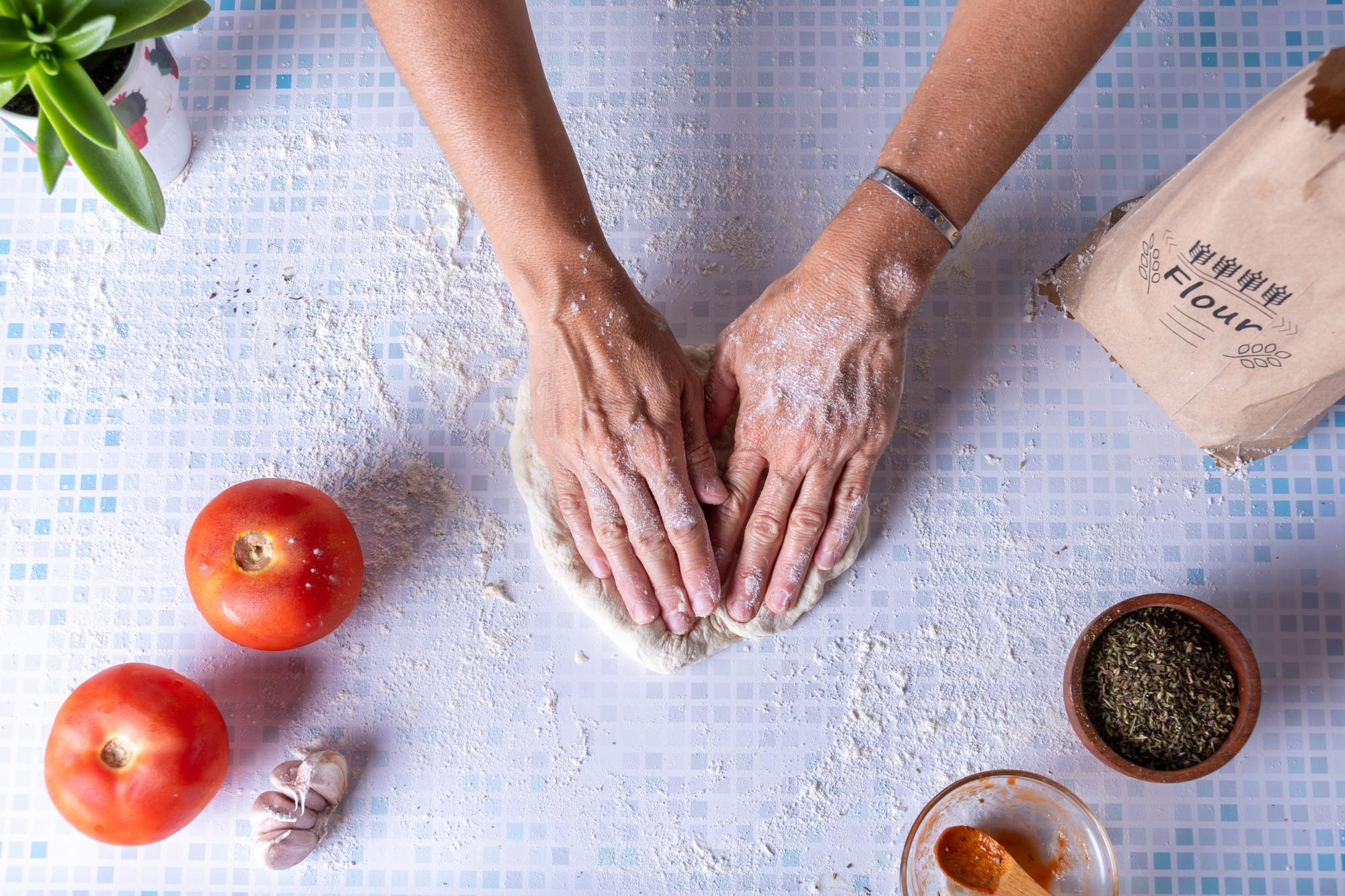 hands kneading dough on floured board