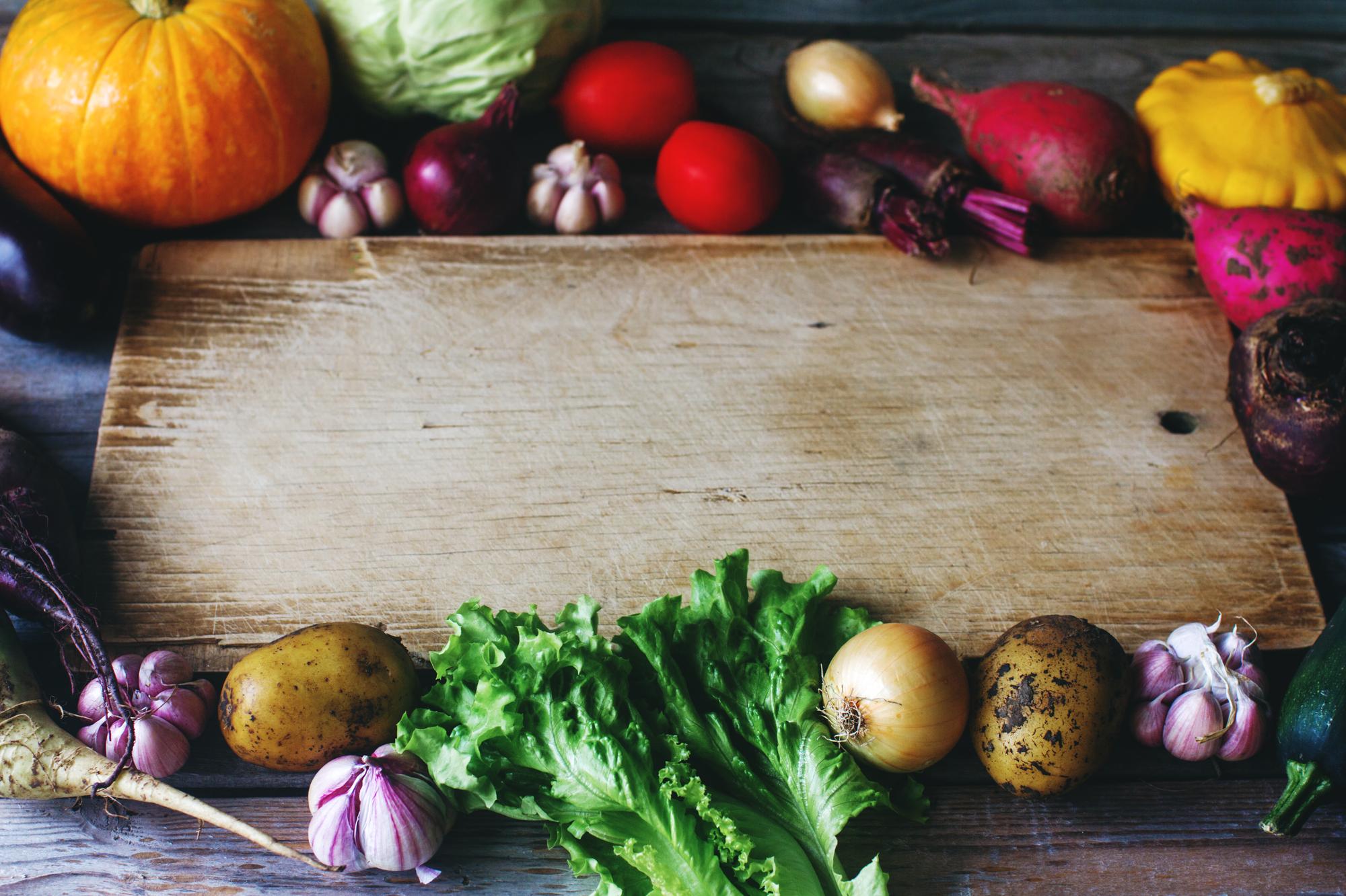 wooden board with seasonal vegetables and recipe cards